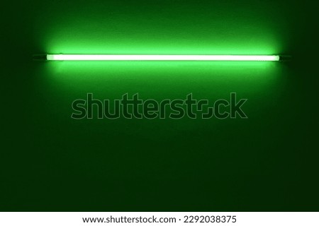 green neon light bulb on white wall.