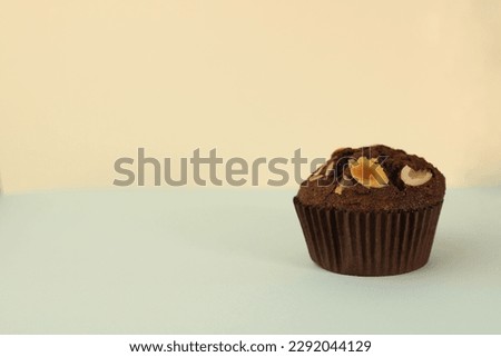fragrant homemade sweet
chocolate cupcake in a brown wrapper with nuts on a light background.