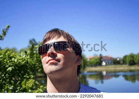 Portrait of a young guy in sunglasses. City lake in Kolomyia