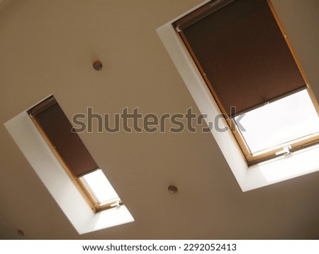 Roller blinds on roof windows close up in the interior. Roller shades for skylights. Brown color. Royalty-Free Stock Photo #2292052413