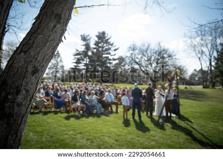 Tree branch in focus with group of people gathered for a wedding faded in the background blurry