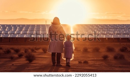 A child and her mother in the fresh open air, beside solar panels on a sunny day at a farm in Desert. Royalty-Free Stock Photo #2292055413