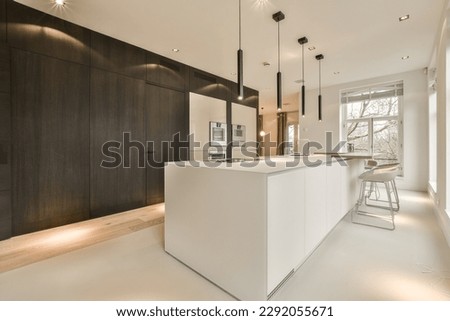 a modern kitchen with white counters and dark wood cabinets in the room is lit by recessed light fixtures Royalty-Free Stock Photo #2292055671