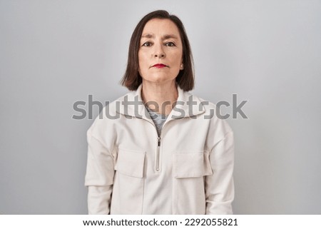 Middle age hispanic woman standing over isolated background relaxed with serious expression on face. simple and natural looking at the camera.  Royalty-Free Stock Photo #2292055821