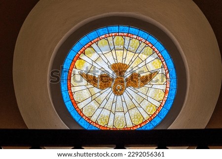 Stained glass window with some kind of bird or dove depicted inside a Christian church in Portugal.