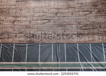 Installation of a warm floor under a laminate. Top view of laminate, film, warm floor