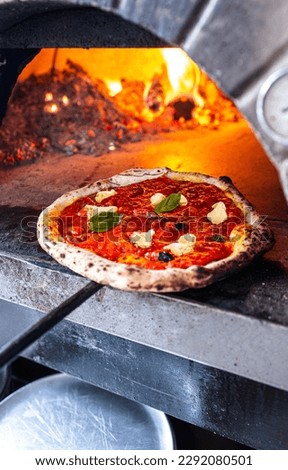 Pizzaiolo pulls out a freshly baked Neapolitan Margherita Pizza from traditional wood-fired oven. Royalty-Free Stock Photo #2292080501