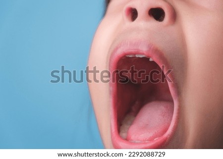 Close-up inside the oral cavity of a healthy child with beautiful rows of baby teeth. Young girl opens mouth revealing upper and lower teeth, hard palate, soft palate, dental and oral health checkup. Royalty-Free Stock Photo #2292088729