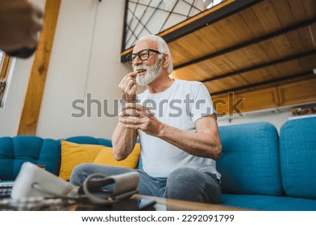One senior man caucasian male grandfather sit at home take drug tablet drink painkillers or vitamin supplement read label medicine real person health and medicine concept copy space Royalty-Free Stock Photo #2292091799