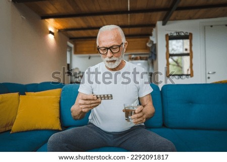 One senior man caucasian male grandfather sit at home hold blister pack of drug tablet painkillers or vitamin supplement read label ready to take medicine real person copy space Royalty-Free Stock Photo #2292091817