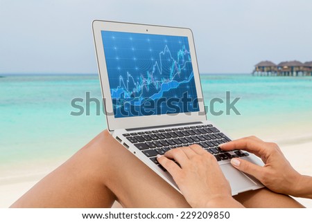 Woman working on a computer at the beach. Sandy beach and forex screen. A concept of the freelance. 