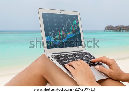 Woman working on a computer at the beach. Sandy beach and forex screen. A concept of the freelance. 
