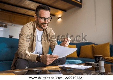 One man mature caucasian male work at home hold paper document sign insurance contract or read report enjoy good news in letter receive official paper about tax refund credit loan approval Royalty-Free Stock Photo #2292104221