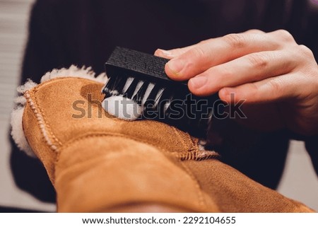 Hands cleaning men's camel suede desert shoe boot with a brush Royalty-Free Stock Photo #2292104655