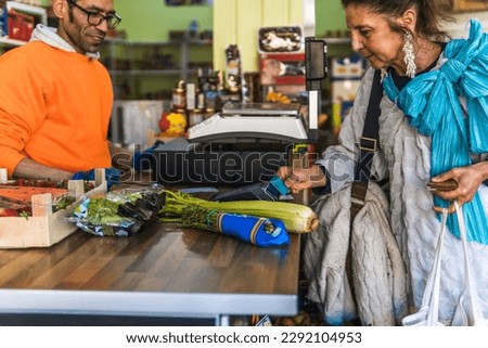 woman paying with a card in a greengrocer