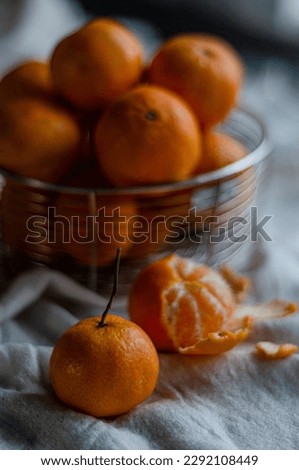 tangerine with a sprig but background with a basket of fruits