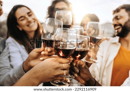 Young people toasting red wine glasses at farm house vineyard countryside - Happy friends enjoying happy hour at winery bar restaurant - Life style concept with guys and girls eating at dinner party Royalty-Free Stock Photo #2292116909