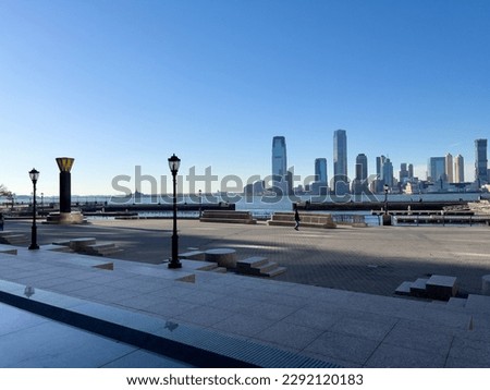 This is a photo taken at Battery Park in New York. The image captures a stunning sunset over the New York City skyline, with skyscrapers in the background.