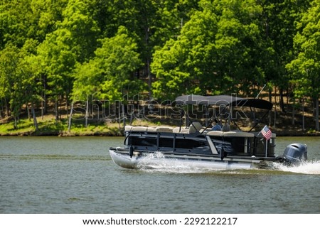 Boater on pontoon boat enjoying summer day on Lake. Pontoon party boat cruising on freshwater lake. Royalty-Free Stock Photo #2292122217