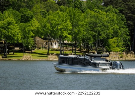 Boater on pontoon boat enjoying summer day on Lake. Pontoon party boat cruising on freshwater lake. Royalty-Free Stock Photo #2292122231