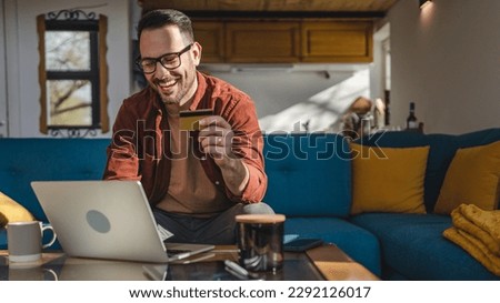 One man adult mature caucasian male sit at home happy smile with laptop computer hold bank credit card online shopping buy on internet concept real people copy space e-commerce e-banking service Royalty-Free Stock Photo #2292126017