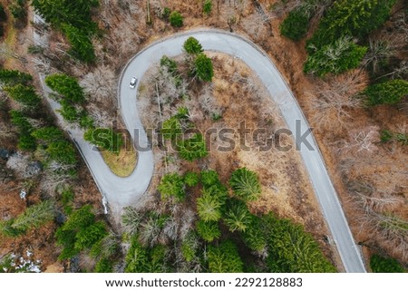an S-shaped road in Slovenia and a passing car. Aerial photography from a drone.