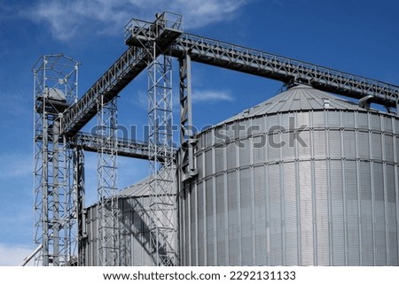 Industrial facilities of feed and flour mills. Close-up of steel grain storage silos with conical bottom, can be used for various purposes. Royalty-Free Stock Photo #2292131133