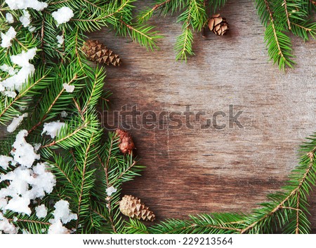 Christmas fir tree with cones and snow on a wooden background, selective focus and place for text. Toned 