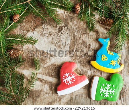 Homemade christmas gingerbreads painted as a blue horse, a red hat and green boot on the wooden background with fir branches. Selective focus and place for text