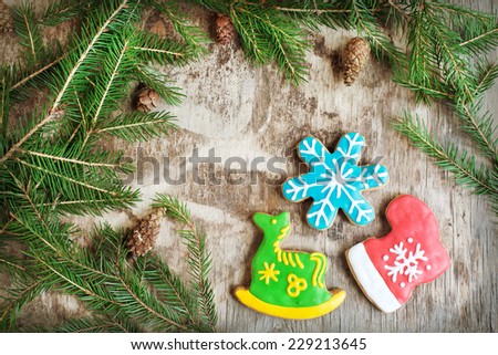 Homemade christmas gingerbreads painted as a green horse, a red boot and blue snowflake on the wooden background with fir branches. Selective focus and place for text. Toned