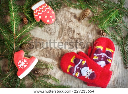Homemade christmas gingerbreads painted as a red hat and boot and and and little red mittens with Santa Claus on the wooden background with fir branches. Selective focus and place for text. Toned