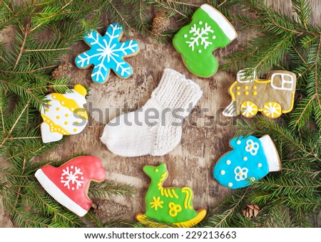Homemade christmas gingerbreads painted as a horse, a hat and boot, locomotive, tree toy, snowflake and sock on the wooden background with fir branches. Selective focus and place for text. Toned