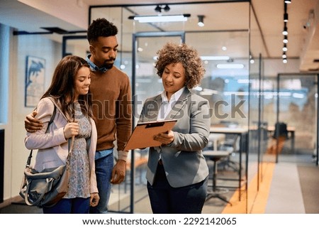 Happy insurance agent and African American couple analyzing documents on a meeting in the office. Royalty-Free Stock Photo #2292142065