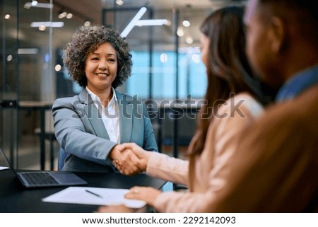 Happy financial advisor shaking hands with her clients on a meeting in the office. Royalty-Free Stock Photo #2292142093