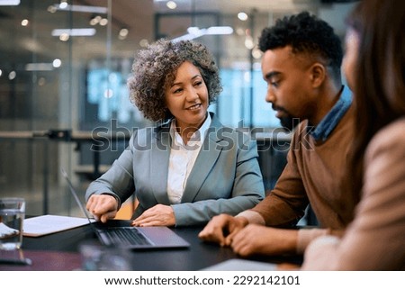 Happy financial advisor and African American couple using laptop on a meeting in the office. Royalty-Free Stock Photo #2292142101