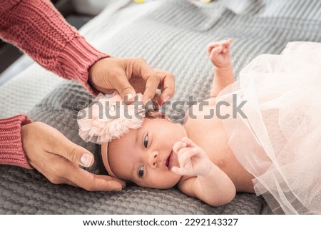 Hands of a mother placing a bow to a baby in pink ballet dress. High quality photo