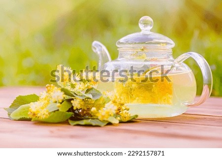glass of refreshing linden tea with linden flowers on a wooden table in a garden Royalty-Free Stock Photo #2292157871