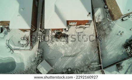 Looking down from an aerial view at houses and backyards in the suburbs during winter
