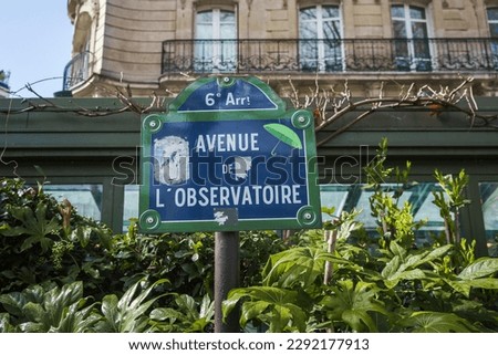 Avenue de L'Observatoire street sign among the green leaves in Paris, France.