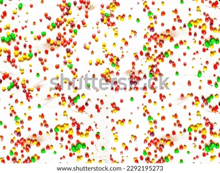 Rainbow colored candy sprinkled on a white background.