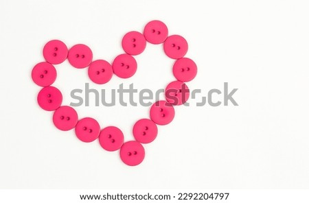Shape of heart from pink buttons on a white background. Symbol of love