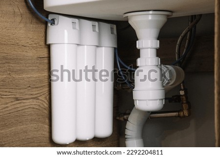 Home water filtration plant close-up. Small water filters under the sink in the kitchen Royalty-Free Stock Photo #2292204811