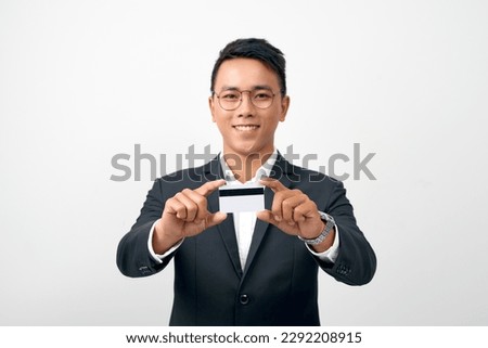 Portrait of handsome young businessman holding credit card over white background