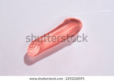 Three strokes of lip gloss on a beige background. Royalty-Free Stock Photo #2292228591
