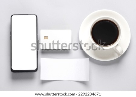 Smartphone, White empty bank card with chip, cup of coffee, chack tape on a gray background. Flat lay business concept. Online shopping. Top view