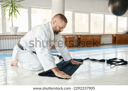 Aikido master folding kimono hakama after training class Royalty-Free Stock Photo #2292237905