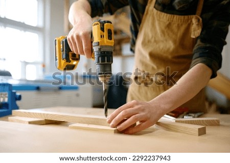 Carpenter working with drill leaning over table at carpentry workshop Royalty-Free Stock Photo #2292237943