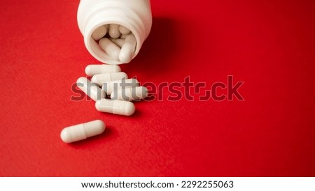 Pills in a jar, take medicine every day on a red background. Tablet container.
