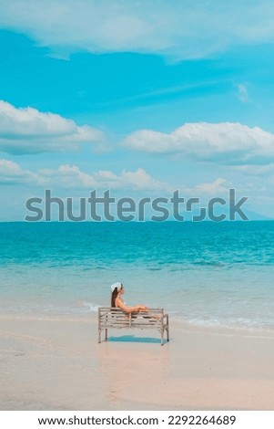 Alone woman sitting on a chair enjoying the blue ocean view at the beach. travel and summer vacation pictures at Kho mun nork ,Thailand