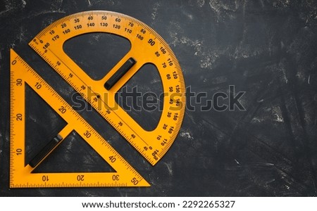 Protractor and triangle ruler on blackboard, flat lay. Space for text
